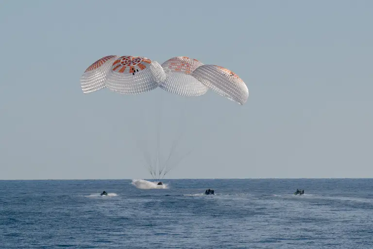 SpaceX Dragon spacecraft with parachutes lands in the ocean off Florida on 18 March 2025, carrying Crew-9 astronauts after their ISS mission, with recovery boats nearby.